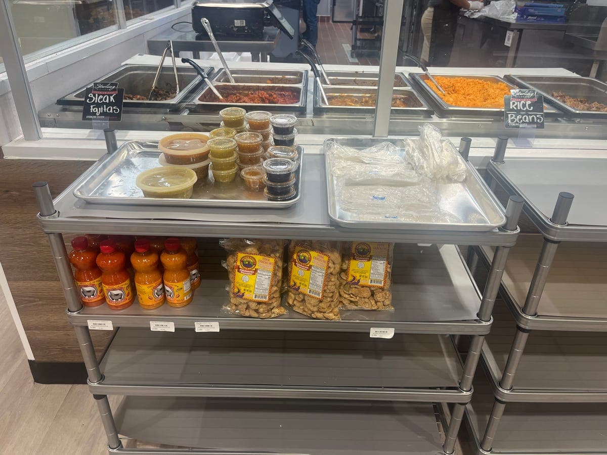 Hot food counter with fajitas, rice, and salsas at Los Portales